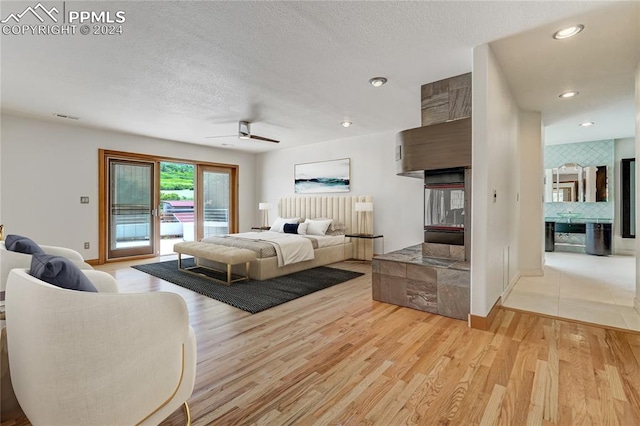 bedroom with light hardwood / wood-style floors, access to exterior, ceiling fan, and a textured ceiling