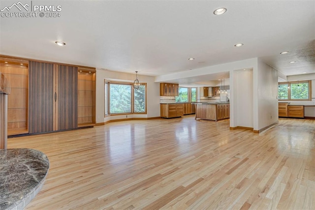 unfurnished living room with light hardwood / wood-style flooring and a chandelier