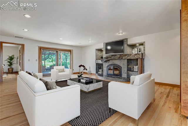 living room featuring light hardwood / wood-style flooring and a tiled fireplace