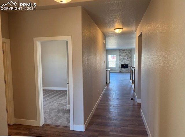 hallway with dark wood-style floors, baseboards, and a textured ceiling