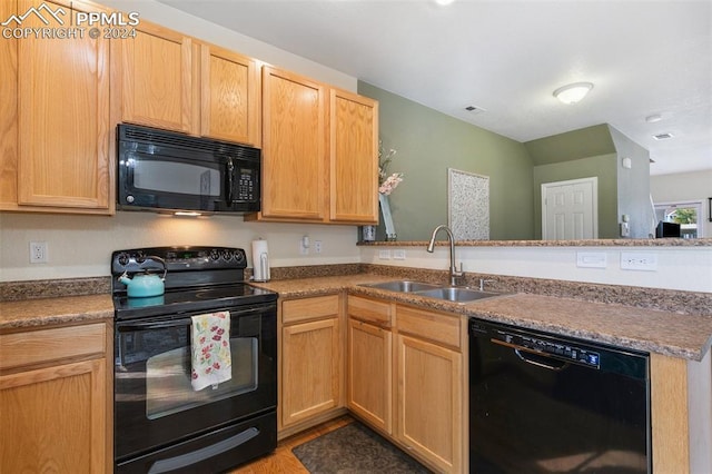 kitchen featuring black appliances, kitchen peninsula, and sink