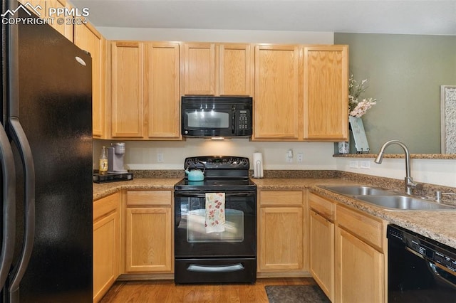 kitchen with black appliances, sink, light brown cabinets, and light hardwood / wood-style floors