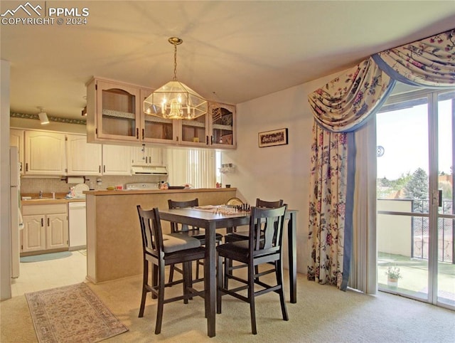 dining area with light colored carpet, a notable chandelier, and sink