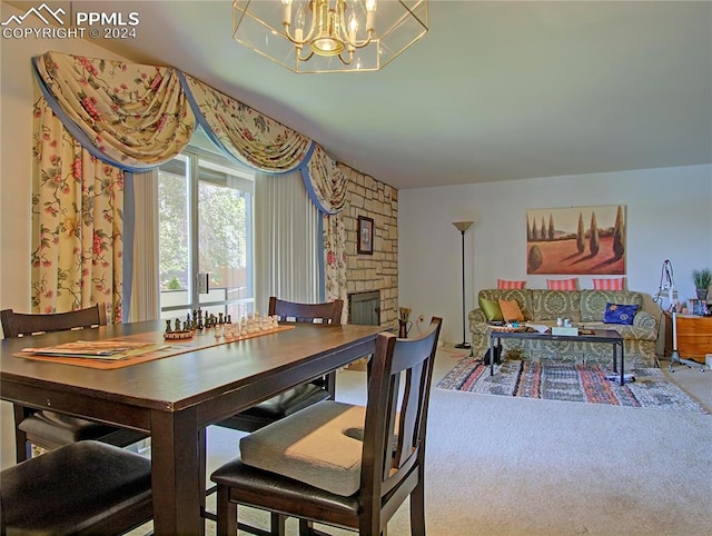 dining area featuring carpet flooring, a notable chandelier, and a stone fireplace