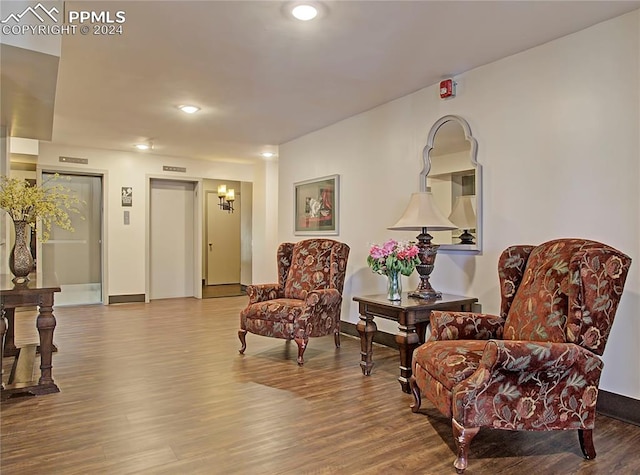 sitting room featuring an inviting chandelier and hardwood / wood-style flooring