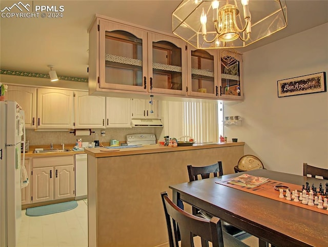 kitchen featuring backsplash, decorative light fixtures, white appliances, a notable chandelier, and sink