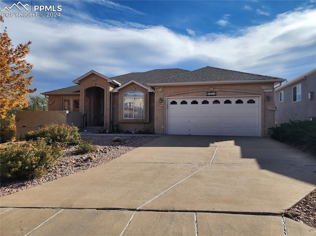 ranch-style home with a shingled roof, an attached garage, driveway, and stucco siding