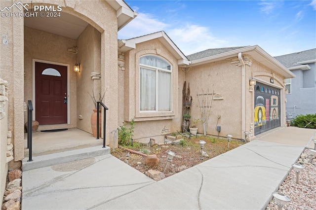 view of exterior entry with stucco siding and an attached garage