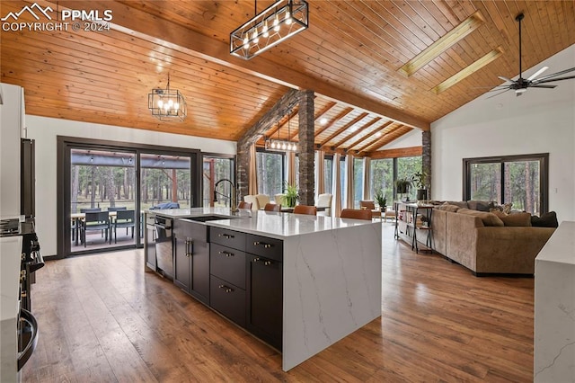 kitchen with a skylight, ceiling fan with notable chandelier, a healthy amount of sunlight, and a center island with sink