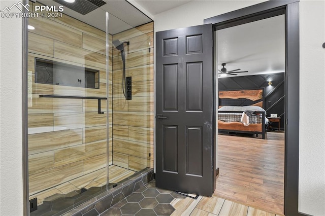 bathroom featuring a shower with shower door, ceiling fan, and hardwood / wood-style flooring