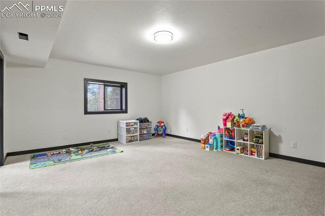 recreation room featuring carpet flooring and a textured ceiling