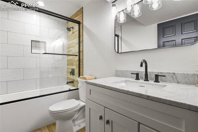 full bathroom with toilet, shower / bath combination with glass door, wood-type flooring, vanity, and a textured ceiling