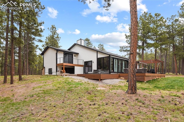 rear view of property featuring a wooden deck and a lawn