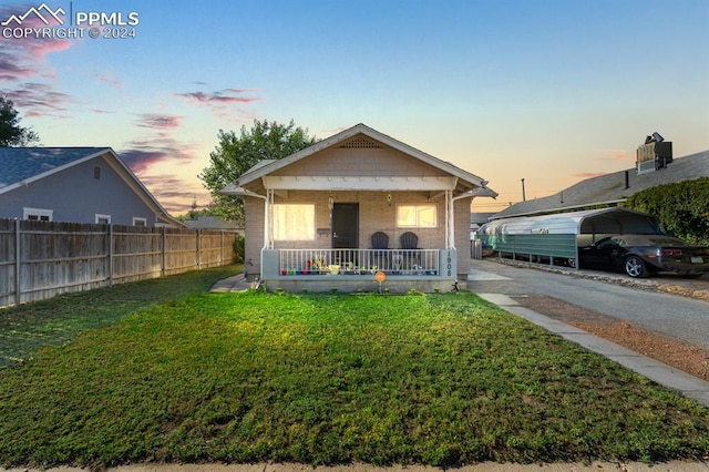 view of front facade featuring a yard, covered porch, and a carport