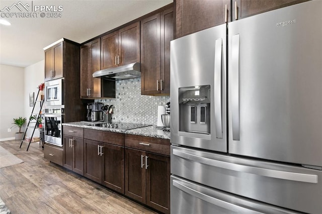 kitchen with light hardwood / wood-style flooring, light stone countertops, stainless steel appliances, dark brown cabinets, and decorative backsplash