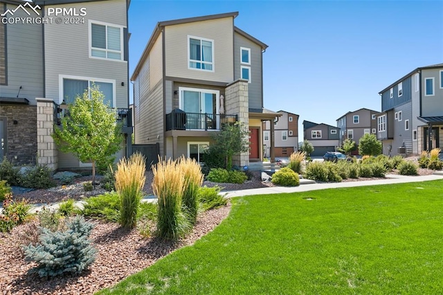 view of front of property with a front lawn, a balcony, and central AC unit