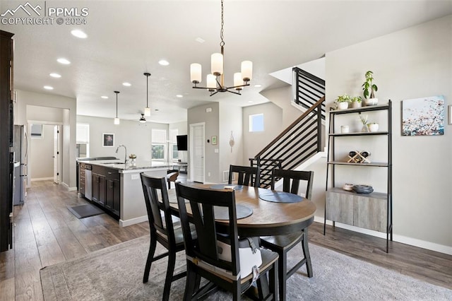 dining room with ceiling fan with notable chandelier, hardwood / wood-style floors, and sink