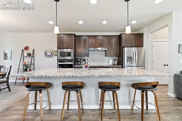 kitchen with a breakfast bar area, stainless steel appliances, and light hardwood / wood-style floors