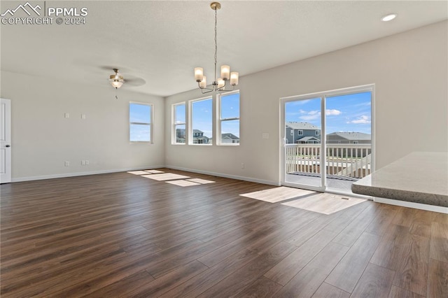 unfurnished living room featuring ceiling fan with notable chandelier and dark hardwood / wood-style floors