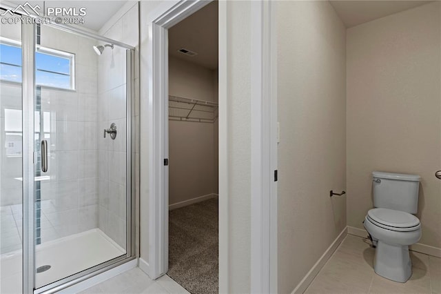 bathroom with toilet, a shower with shower door, and tile patterned floors