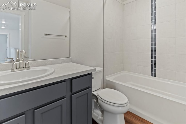 full bathroom with tiled shower / bath, vanity, toilet, and wood-type flooring