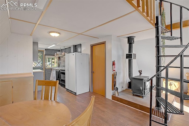 dining room with a wood stove, wood walls, and light hardwood / wood-style floors