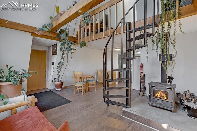 interior space with a wood stove, beamed ceiling, and hardwood / wood-style flooring