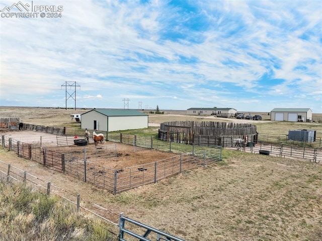 view of yard with a garage, a rural view, and an outbuilding