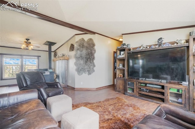 living room with ceiling fan, lofted ceiling, a wood stove, hardwood / wood-style flooring, and crown molding