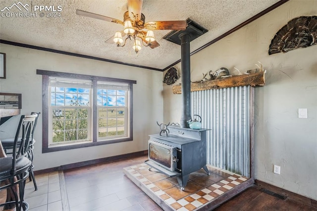 interior space with a textured ceiling, ornamental molding, and a wood stove