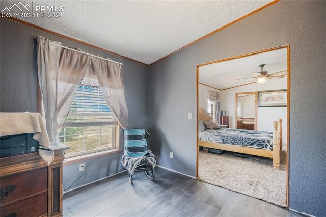 bedroom with ceiling fan, lofted ceiling, wood-type flooring, a textured ceiling, and crown molding