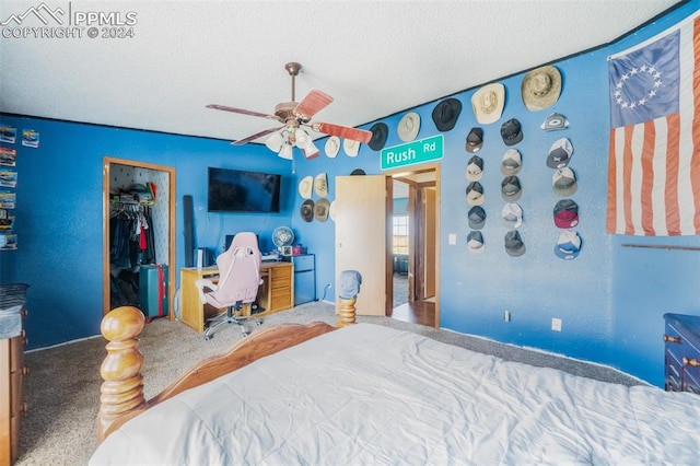 bedroom with a closet, a textured ceiling, carpet, a walk in closet, and ceiling fan