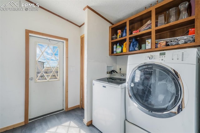 washroom with a textured ceiling, ornamental molding, and washing machine and clothes dryer