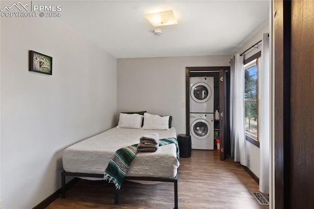 bedroom with stacked washing maching and dryer and hardwood / wood-style floors