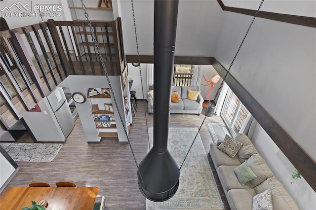 living room featuring a high ceiling, a wood stove, and hardwood / wood-style flooring