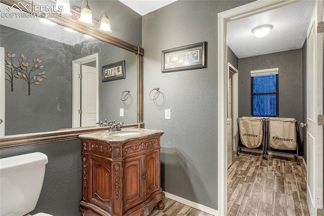 bathroom with wood-type flooring, vanity, and toilet