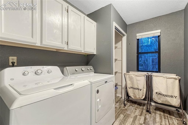 washroom with cabinets, a textured ceiling, light hardwood / wood-style floors, and washing machine and clothes dryer