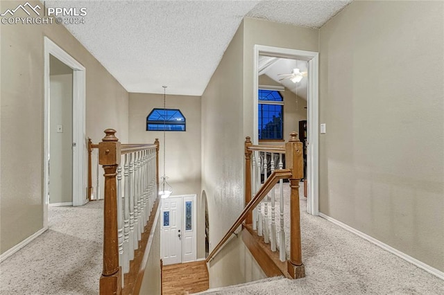 staircase with vaulted ceiling, a textured ceiling, and carpet flooring