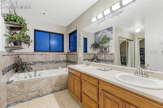 bathroom with vanity, a relaxing tiled tub, and tile patterned flooring