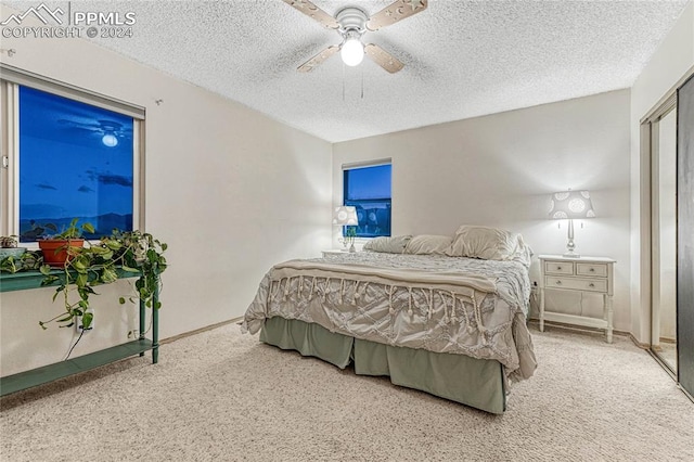 carpeted bedroom featuring ceiling fan and a textured ceiling