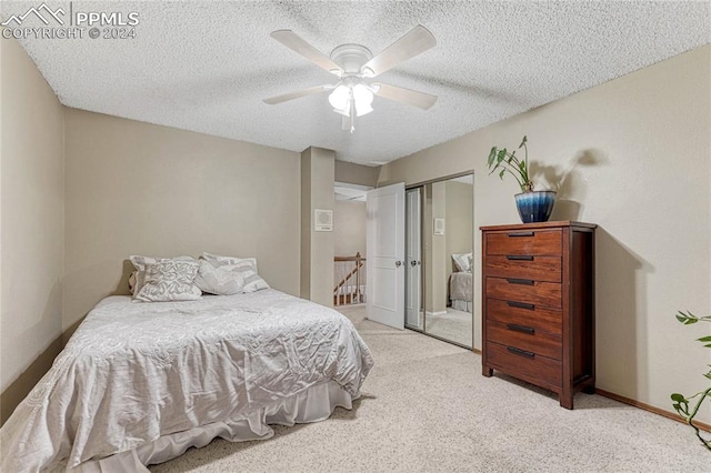 bedroom with ceiling fan, light colored carpet, a textured ceiling, and a closet