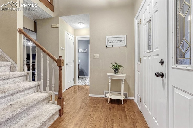 foyer entrance featuring a textured ceiling and light hardwood / wood-style floors