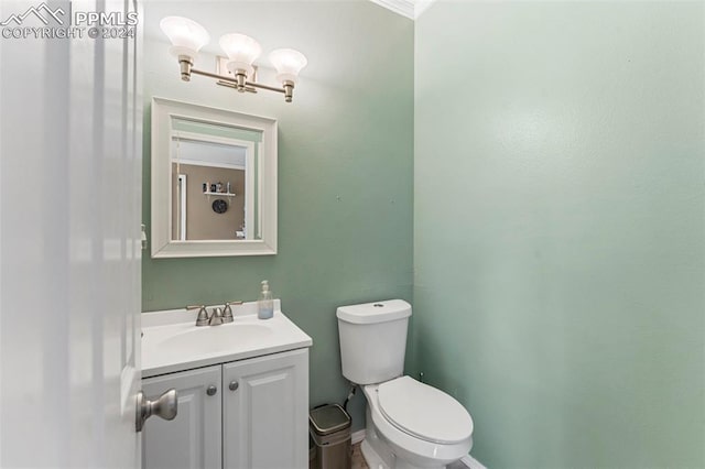 bathroom with vanity, crown molding, and toilet