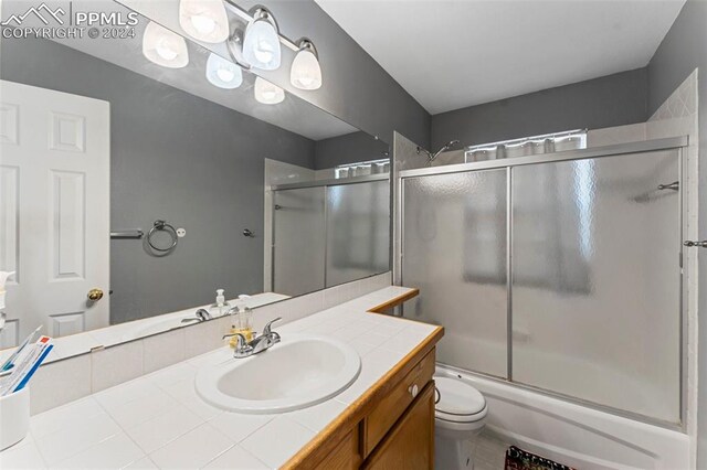 full bathroom featuring shower / bath combination with glass door, vanity, and toilet