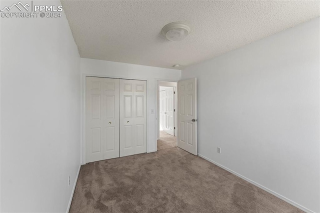 unfurnished bedroom featuring a textured ceiling, a closet, and carpet