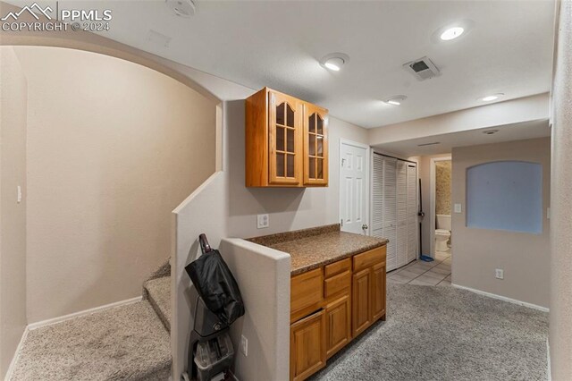 kitchen with light carpet and dark stone countertops