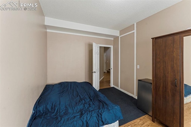 bedroom with a textured ceiling and wood-type flooring