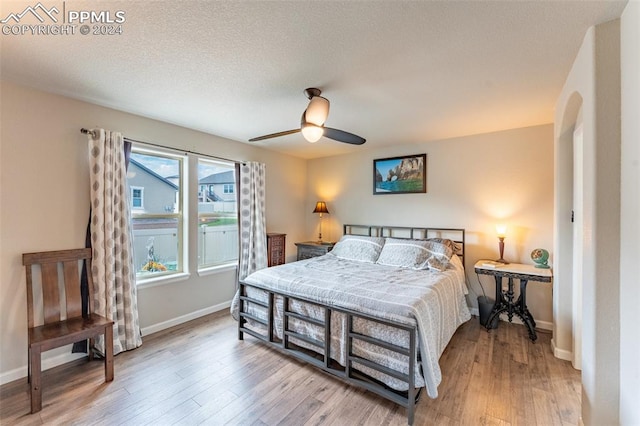 bedroom featuring light wood-type flooring, ceiling fan, and a textured ceiling