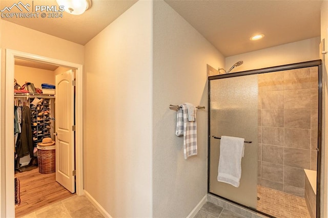 bathroom with wood-type flooring and a shower with door