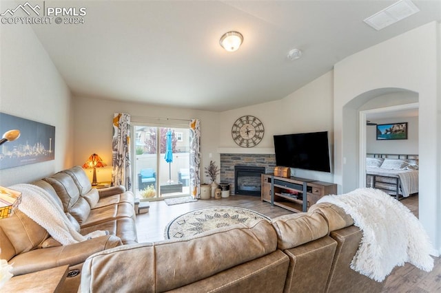 living room with wood-type flooring and a stone fireplace